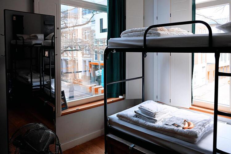 Chambre de l'auberge de la Canebière avec un lit mezzanine pour deux personnes, un mirroir, deux fenêtres parfait pour profiter de la ville. 