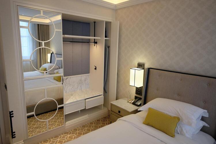 Photo d'une chambre de l'hôtel les mouettes, on y voit un lit propre et comfortable, et des mobiliés pratique et jolie tel qu'une grande armoire avec un mirroir qui offre beaucoup de rangement, une table de nuit avec un téléphone etc.  